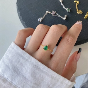 Detail of s925 silver chain ring with green pear-shaped zircon on model's finger