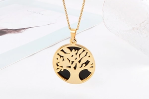 Detailed shot of a gold tree of life pendant necklace featuring a black round background