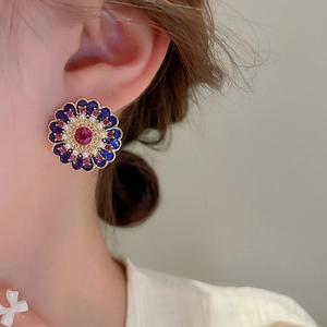 Macro detail of vintage floral earring with purple enamel and center red zircon stone