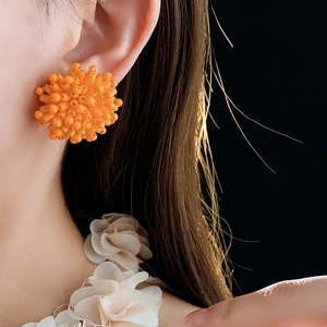 Close-up of orange beaded fireworks stud earrings showing intricate textures and design