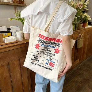 Canvas tote bag with vintage print shown on shoulder in a warm cafe setting