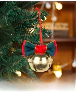 Close-up of golden Christmas bell with red and green bow hanging on a pine tree branch