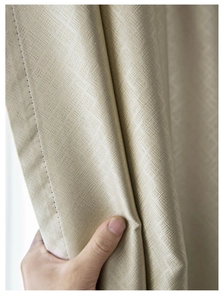 Detail shot of beige blackout curtain fabric with thick square woven texture and drape