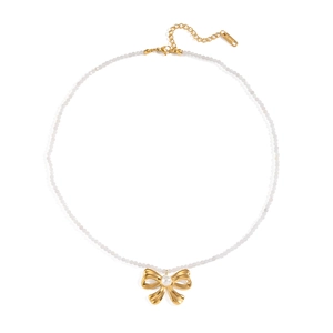 Detailed close-up of a white beaded necklace with golden bow pendant and pearl center