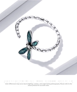Macro view of dragonfly ring featuring blue enamel wings and beaded silver band