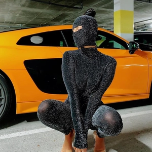 Combinaison noire à paillettes avec masque intégral posant près d'une voiture