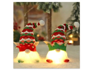 Close-up of a glowing Christmas gnome plush with red and green hats and golden bells