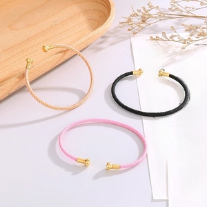 Detailed view of woven C-shape bracelets with golden metal ball ends in various colors