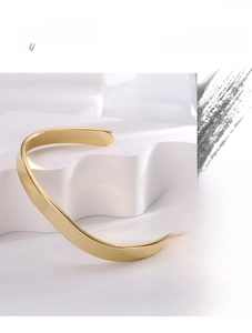 Detail of a minimalist 18K gold plated brass open cuff bracelet with a glossy finish