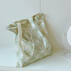 Detail of floral canvas bag featuring pink tulips and white poodles with woven shoulder strap