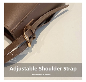 Detail view of adjustable dark brown leather shoulder strap with metallic buckle
