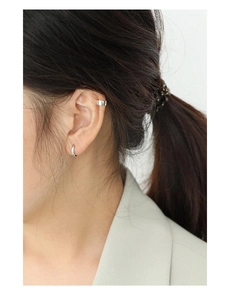 Close-up of minimalist S925 sterling silver hoop earring and wide ear cuff on model ear