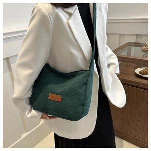 Detailed macro view of dark green corduroy tote bag with brown leather fashion label patch