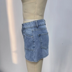 Detail view of high waist denim skirt side pocket and stitching on blue denim fabric