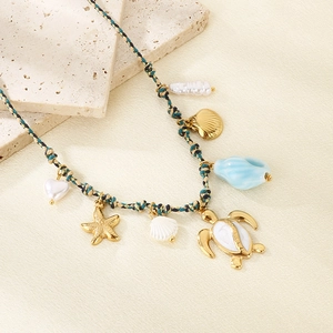 Detail of woven ocean necklace with gold sea turtle pendant, starfish, and white pearls