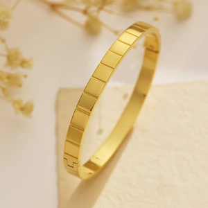 Dettaglio del bracciale placcato oro 18k con texture geometriche e chiusura laterale sicura
