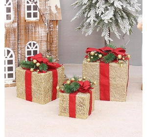 Detailed view of gold Christmas gift boxes with red ribbons and pine needle accents