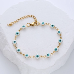 Gold stainless steel evil eye charm bracelet with blue enamel amulets on white rock