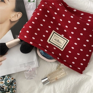 Detail of red polka dot pleated cosmetic bag with Pleasant Time label on fabric