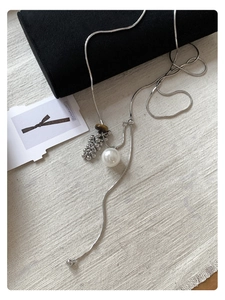 Detail of tiger eye stone and pearl pendant on a silver chain over a jewelry box