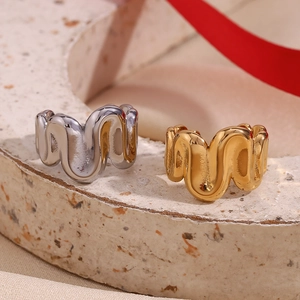 Close-up of wavy 18K gold and silver plated stainless steel rings on a stone base