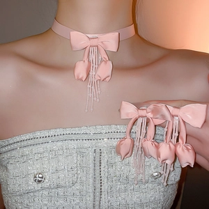 Detailed view of pink fabric bow necklace and tulip tassel earrings set on model