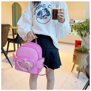 Pink sequin backpack for girls with heart-shaped wings in a lifestyle cafe setting