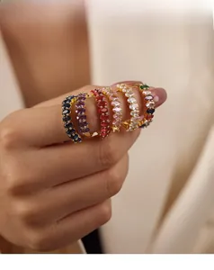 Detail of six stackable gold rings featuring colorful oval-cut zircon stones on female hand