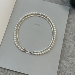 Double-layered pearl necklace with zircon details displayed on a minimalist background