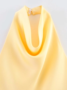 Vue détaillée du haut dos nu en satin jaune avec fermeture à bouton et détails drapés
