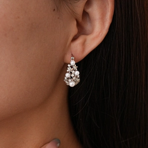 Close-up detail of vintage pearl and rhinestone cluster earrings worn by a model