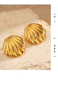 Detailed view of golden seashell stud earrings with textured finish on stone background