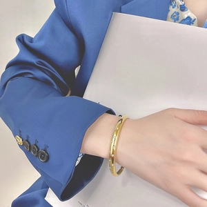 Close-up of gold stainless steel bangle with star-shaped zircon inlays on a model's wrist