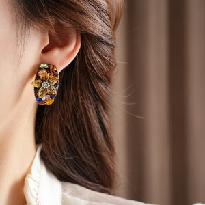 Close-up of vintage flower earrings with colorful gems and pearls on a model