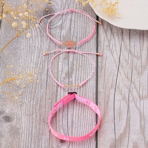 Detail of pink bohemian bracelet set with cross and religious medal on wood texture