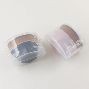 Detail of pink and grey foundation brushes with soft brown bristles in clear storage cases