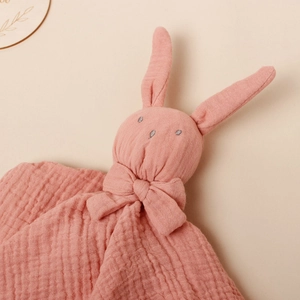 Detailed close-up of pink cotton muslin baby comforter with soft rabbit head and bow