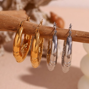 Textured 18K gold and silver chunky C-shaped hoop earrings hanging on a branch