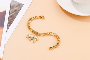 Macro shot of 18K gold chain bracelet featuring a charming elephant charm and lobster clasp