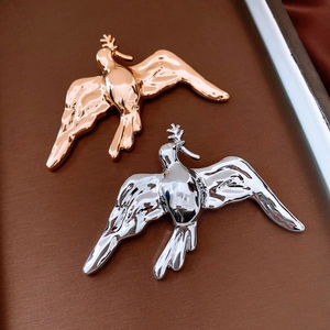Dettaglio macro di spille a forma di uccello in oro e argento con finitura lucida