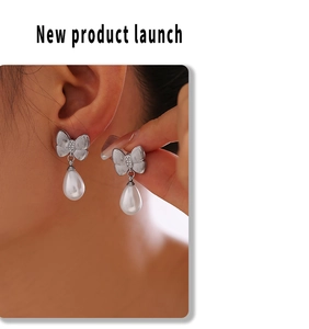 Detail showing elegant bowknot drop earrings with pearls on model's ear in silver finish