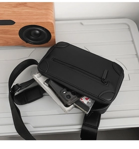 Detail view of black minimalist crossbody bag interior showing phone and manual storage space