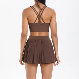 Detail of cross-back coffee brown sports bra and pleated tennis skirt set on a model