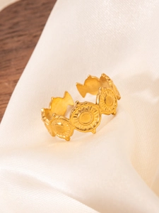 Detail of 18k gold plated sunburst and fish motif ring on white satin fabric