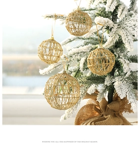 Close-up of golden hollow mesh Christmas ball ornament hanging on a snowy pine tree branch
