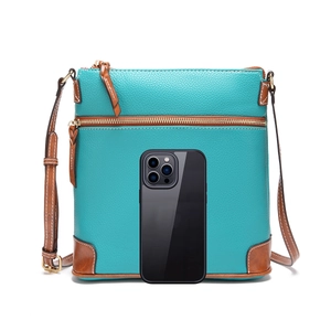 Detailed macro view of pebble textured lake green leather crossbody bag with brown trim