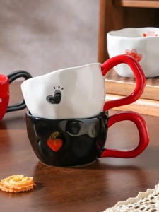 Detail of handcrafted heart pattern ceramic mugs with red handles and textured finish