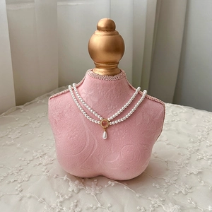 Elegant double-layered pearl necklace with pink gemstone pendant on a velvet neck bust