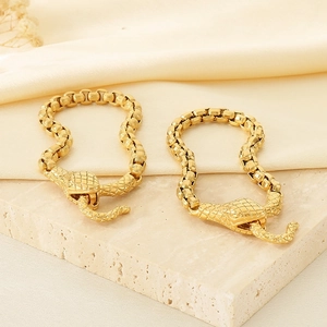 Gros plan du fermoir serpent doré et du bracelet à maillons carrés épais sur socle pierre