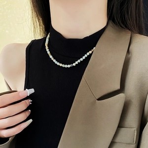 Minimalist beaded pearl necklace with blue and beige beads on a model in a suit